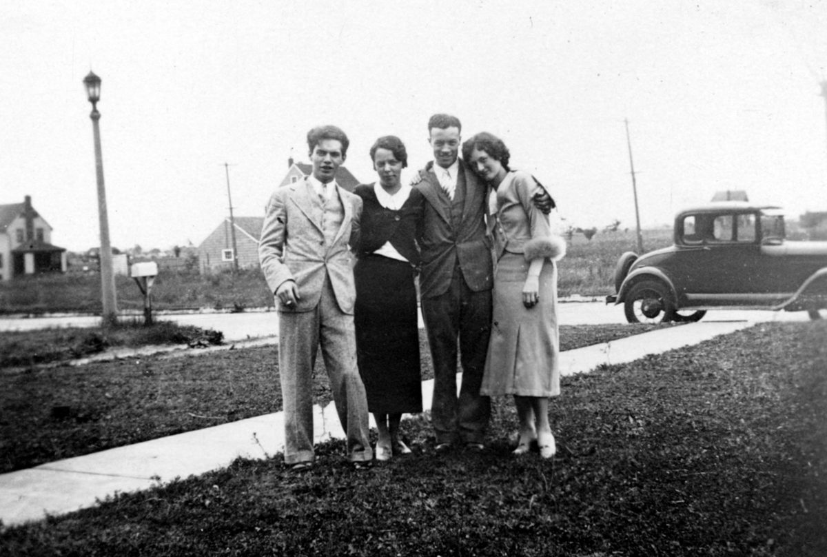 纽约，美国-1月1日，1930年：一个身份不明的家庭站在他们纽约州家前草坪上的复古集体照片，手臂放在彼此的肩膀上，背景中可以看到汽车和道路。