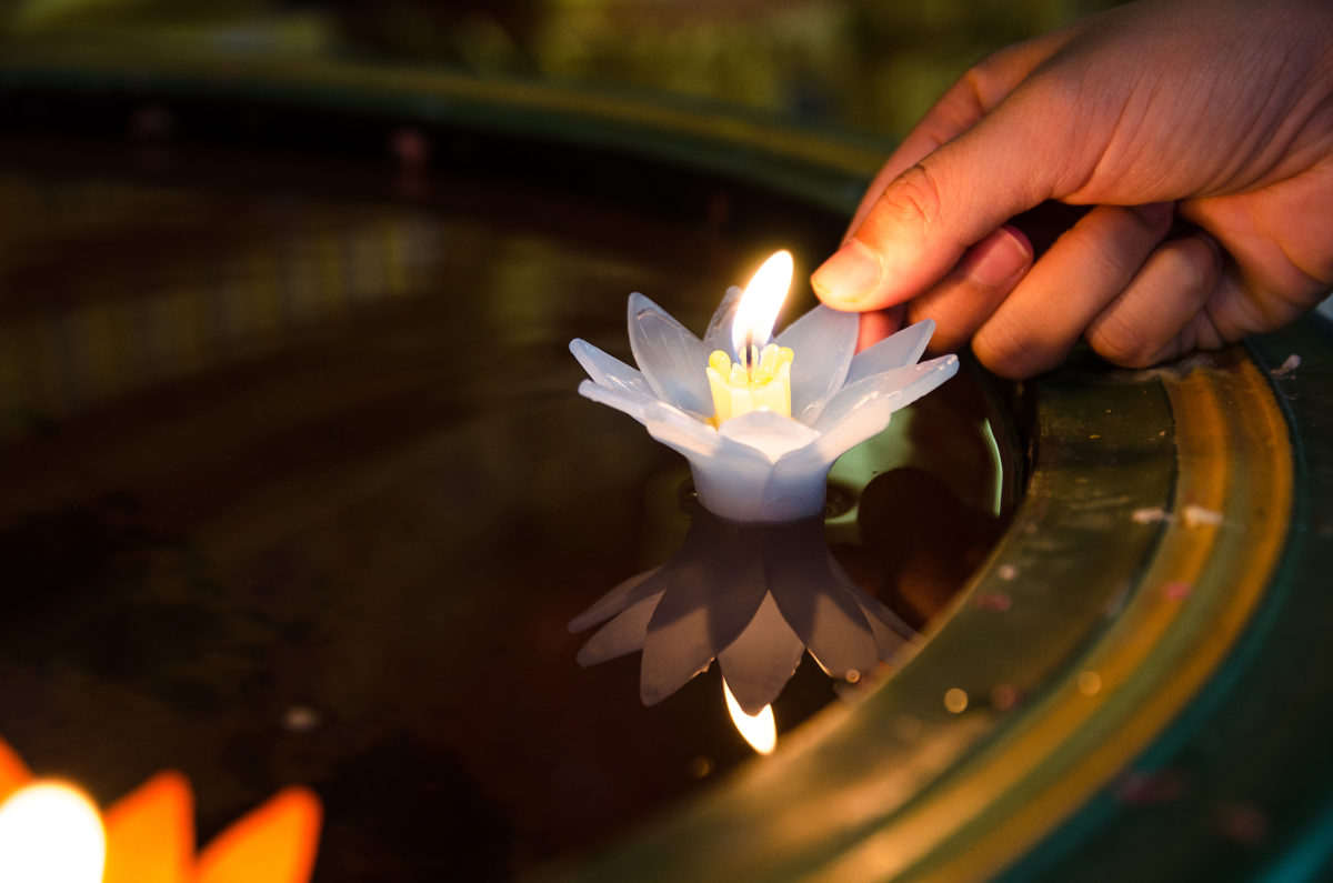 人们手放莲花烛光，在水中飘浮，心平气和。信仰和信念的概念。