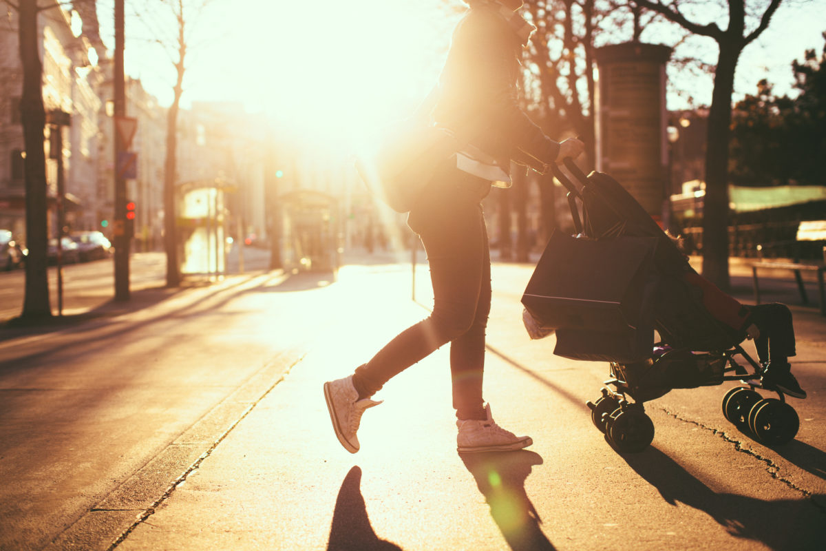 一位现代妈妈和她的孩子在婴儿车里轻松地散步和购物的照片，城市户外