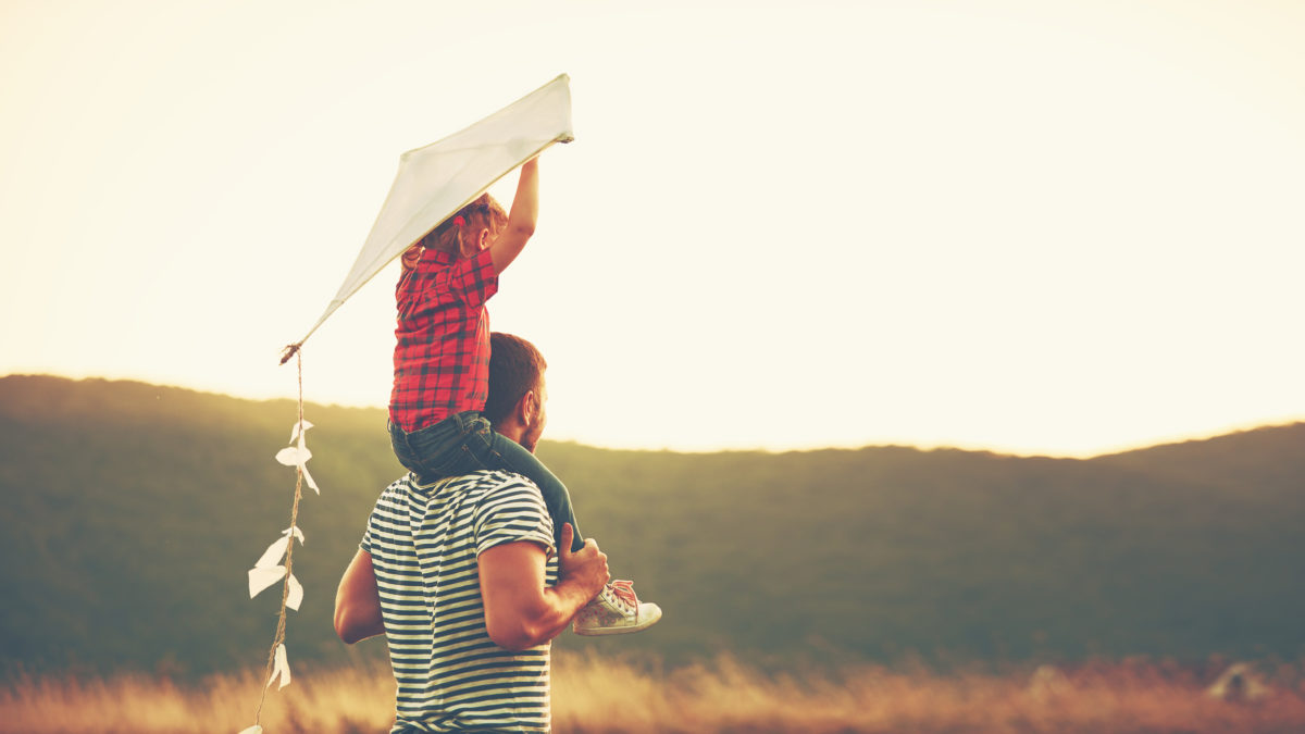 幸福家庭的父亲和孩子在草地上放风筝在夏天的大自然里