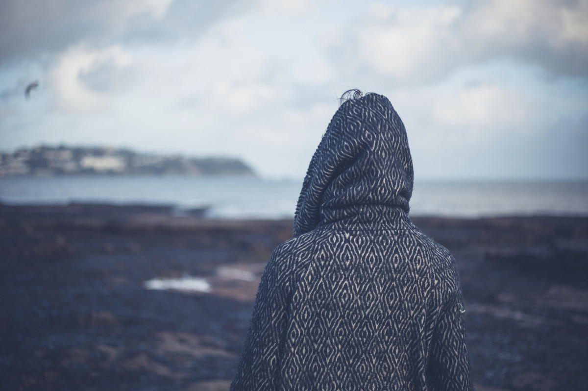 冬天，一位身穿连帽外套的年轻女子在一个引人注目的海滩上散步。