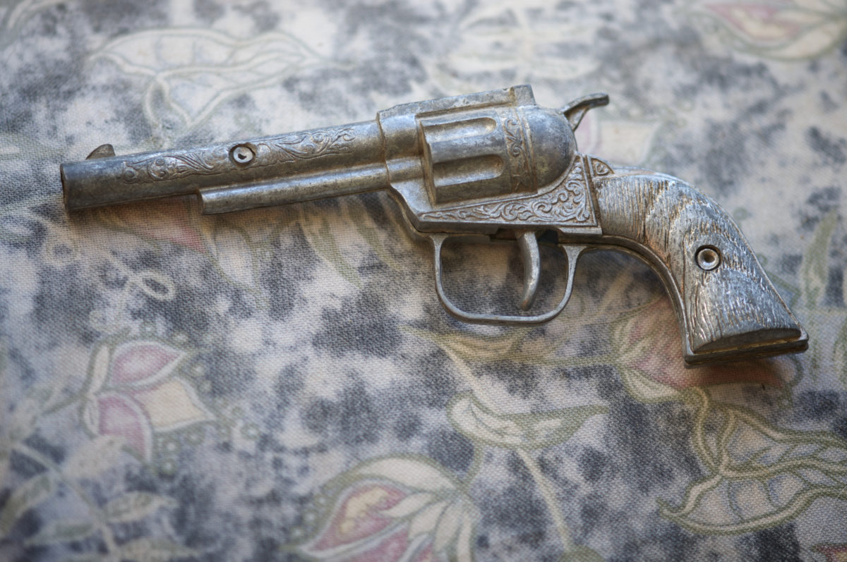 古董玩具枪放在一个风化的旧布背景上