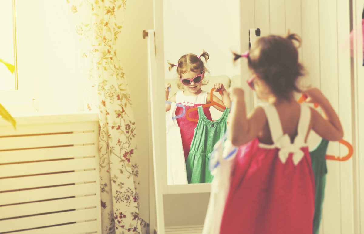 小女孩看着镜子，选择衣服