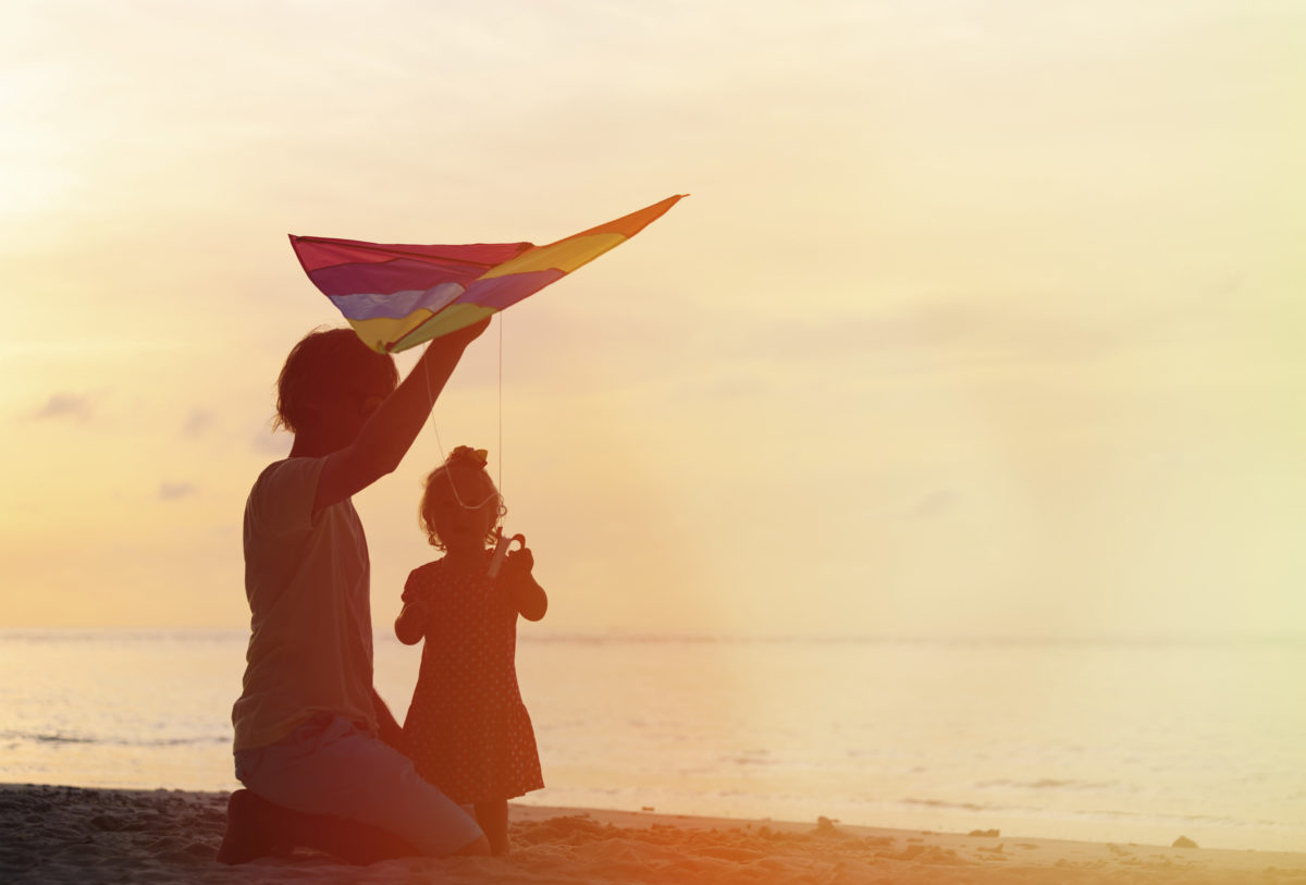 父亲和小女儿在日落时玩放风筝