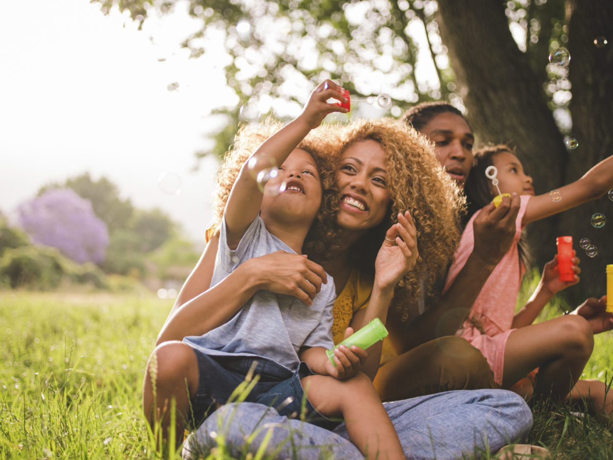 年轻的非裔美国家庭在阳光下分享着一个特殊的时刻，吹着肥皂泡，一起欢笑。