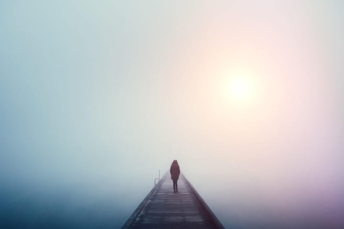 在一个多雾的冬日，一个女人在湖上过桥。
