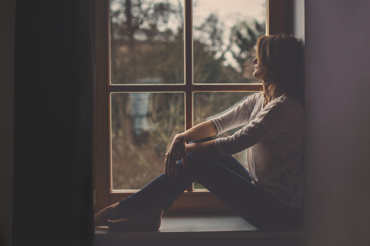 年轻迷人的女人，坐在窗户上，看着外面，孤独的心情