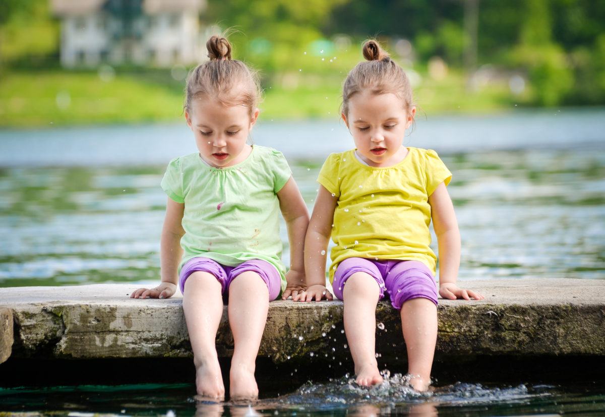 双胞胎女孩在湖岸上锻炼，洒水。