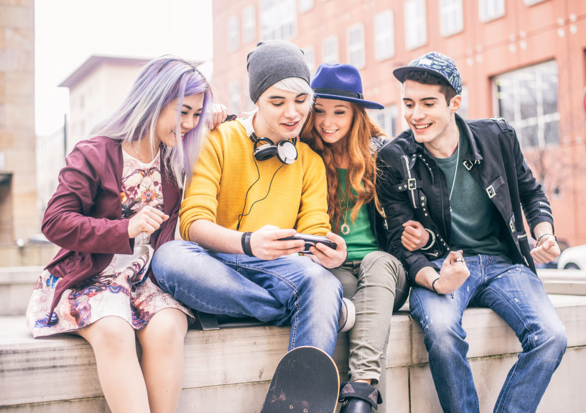 一群青少年在户外玩电子游戏-酷酷的青少年在大学校园里闲逛