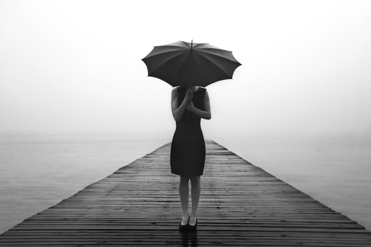 带着雨伞的女人在一个神秘的湖前静静地沉思。