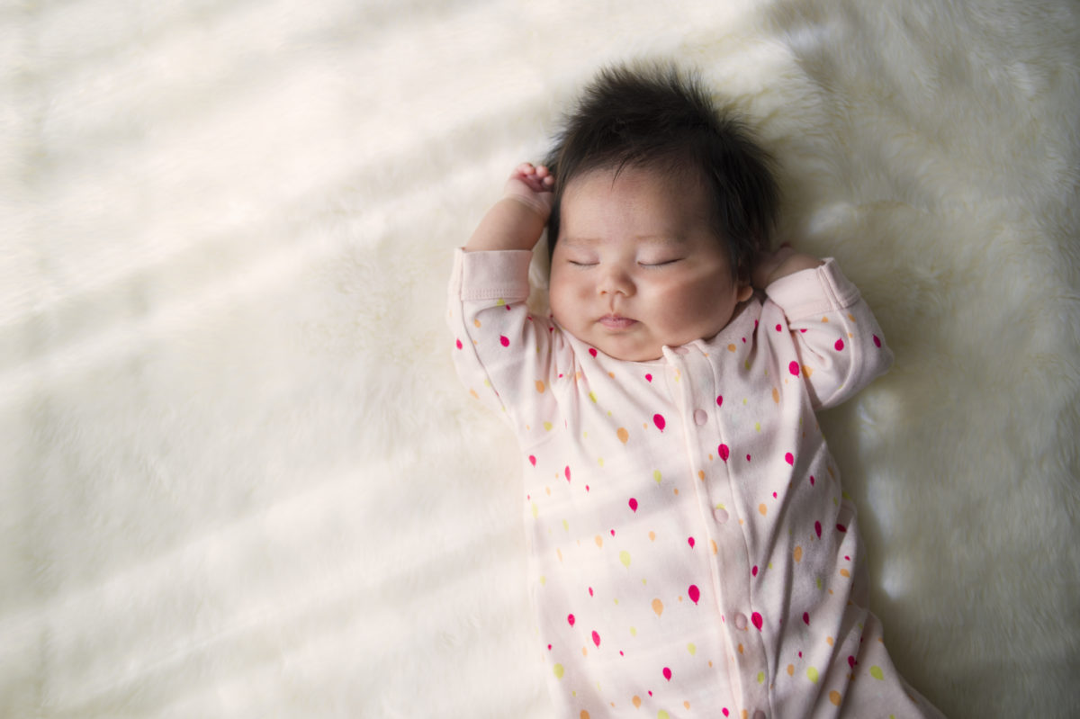 睡觉在一个白色地毯的新出生的婴孩