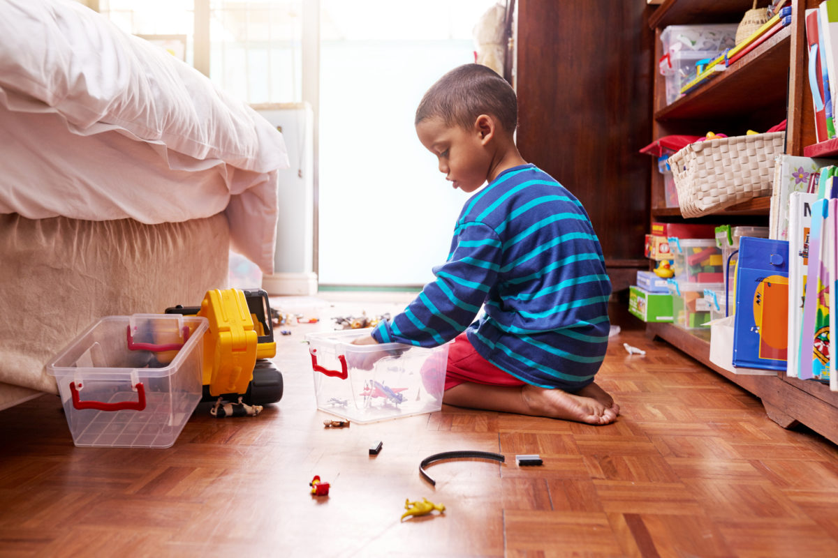 一个小男孩坐在地板上，卧室里有玩具的照片