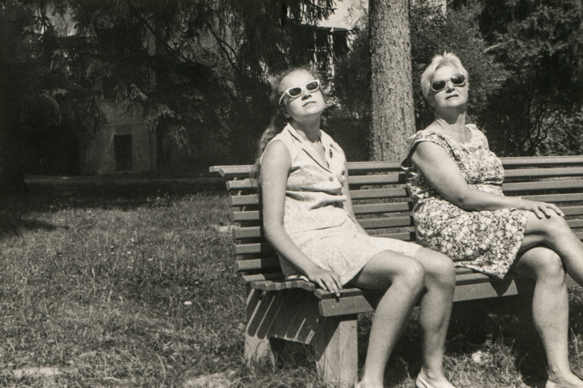 母亲和女儿戴着太阳镜坐在长椅上晒日光浴的复古照片，sixties,Poland