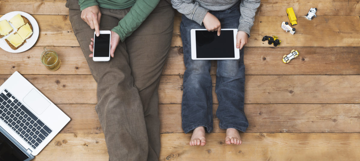 母亲和儿子使用数字媒体的俯视图。现代网络一代沉迷于互联网。