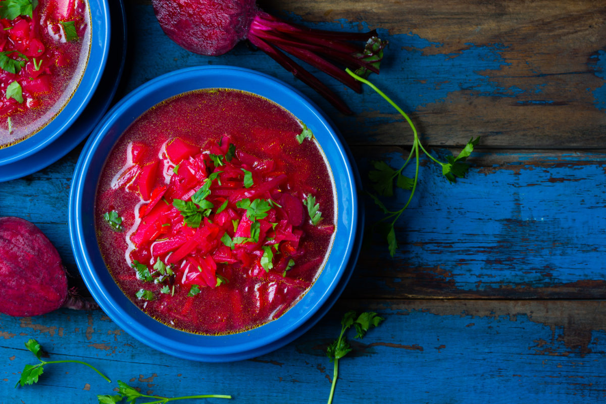 俄罗斯和乌克兰的传统素食红汤-罗宋汤在蓝色盘子的木制背景。俯视图