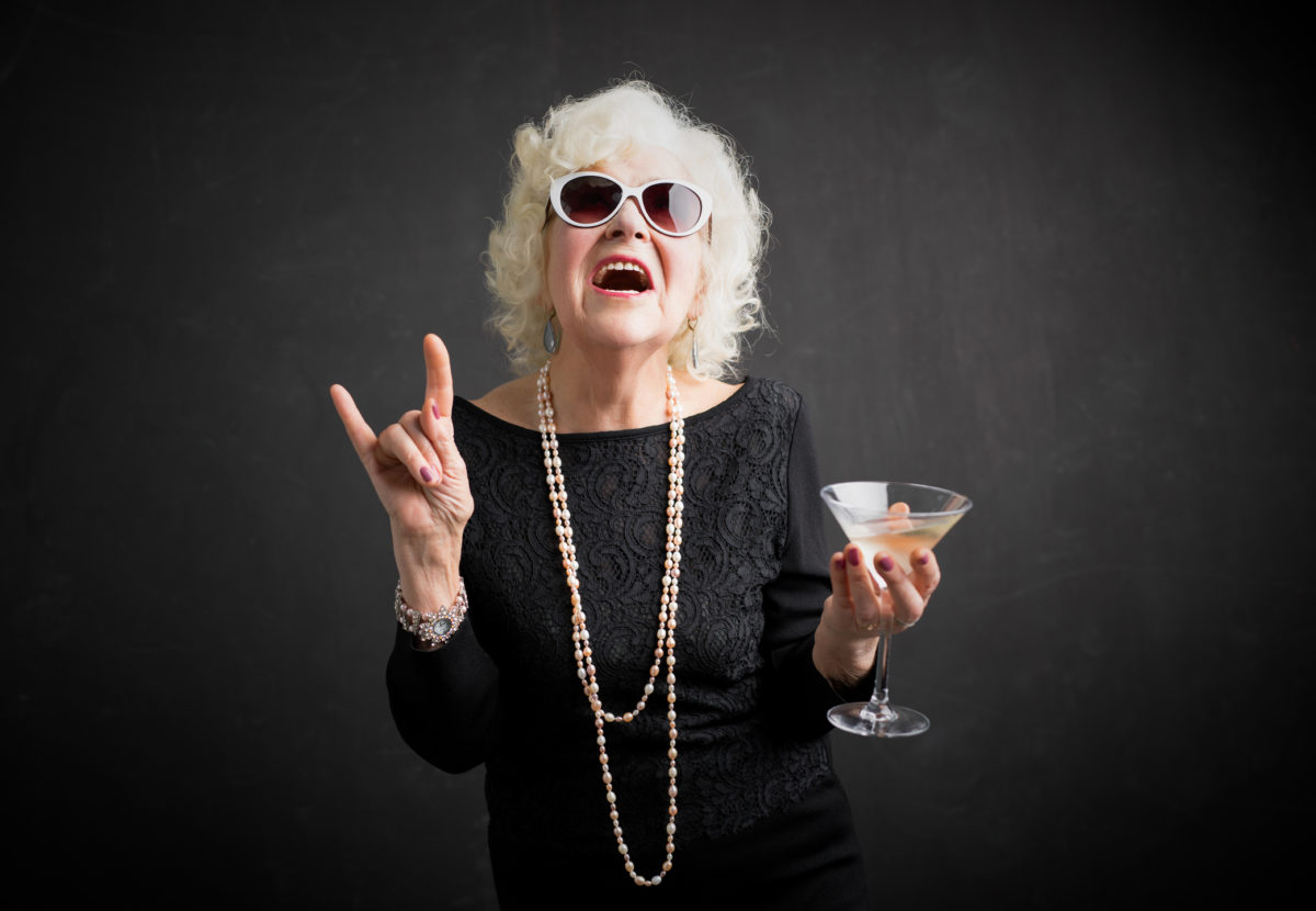 带着太阳镜和饮料的酷奶奶手拿着摇滚标志