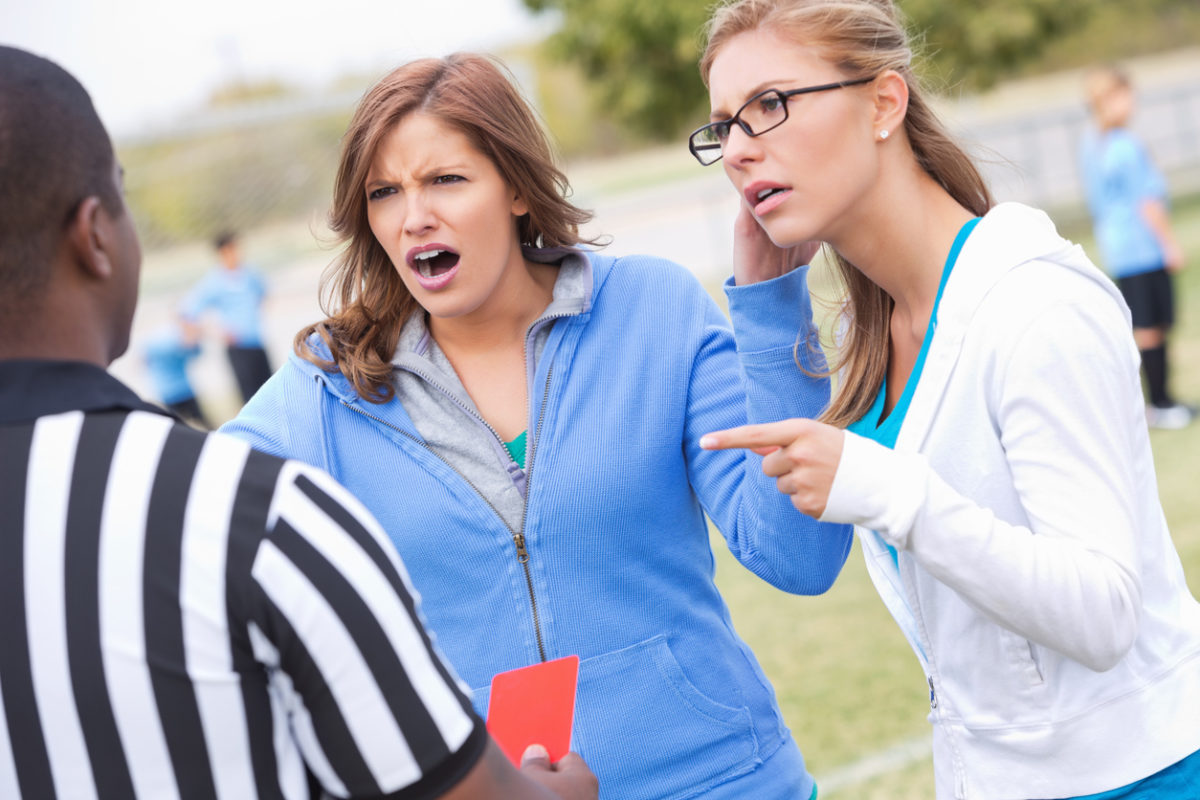愤怒的足球妈妈在孩子们的比赛中对裁判大喊大叫。