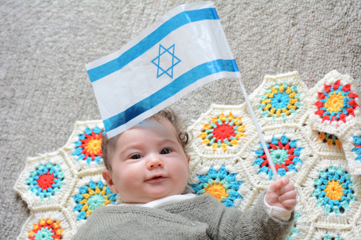 An Israeli newborn baby holding the Israeli flag.Concept photo Israel,Israeli,citizen,patriotism,family,childhood,fertility rate.