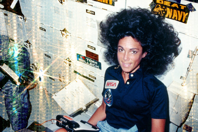 1984年8月30日：特派团专家Judith A Resnik向她的父亲发送了一条消息，从船上发现，在其少女航行STS-41D上。附近，有效载荷专业查理D Walker检查了存储储物柜的内容。（照片由NASA / Space Frontiers / Getty Images）
