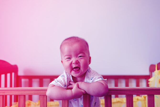 一个sian Baby Girl Standing In Crib Laughing